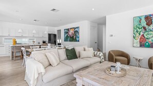 A modern living room with a beige sofa, a coffee table, and a painting on the wall.
