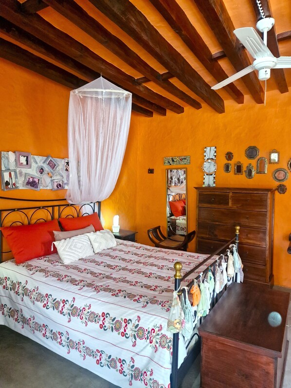 Cozy retreat with a bed, wardrobe, and table, featuring a floral-patterned bedspread and a canopy.