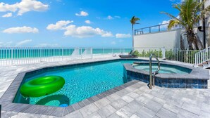 Una piscina con vista al océano, un jacuzzi y una valla blanca.