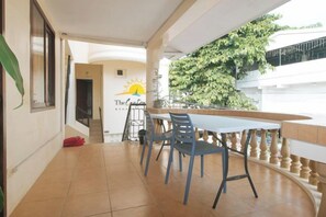 A balcony with a table and chairs, a railing, and a view of a tree. - RedDoorz @ The Central Inn Boracay Island (Boracay Island)