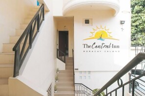 Una escalera conduce a la entrada de un hotel con un letrero que dice 'The Central Inn Boracay Island'.