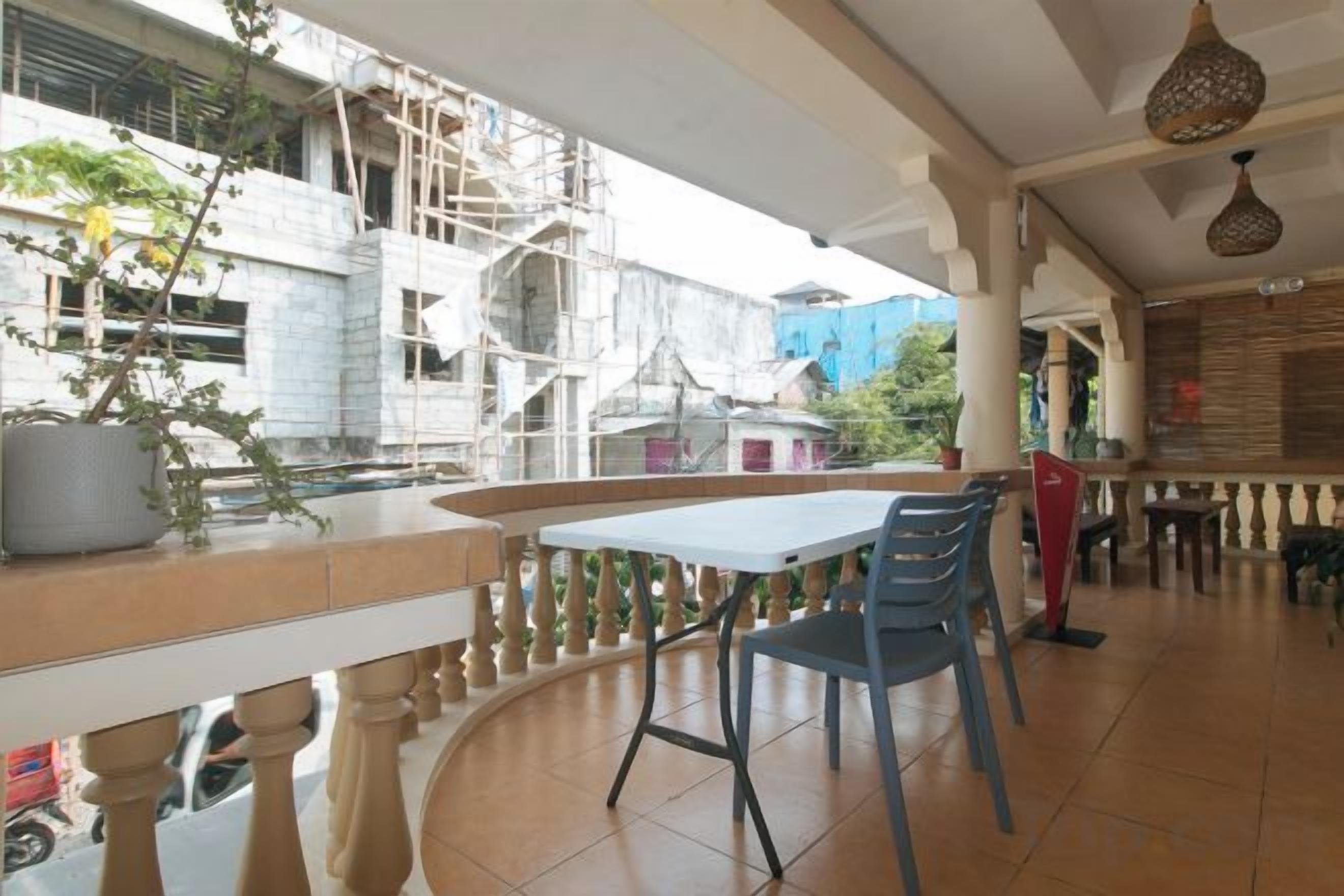 An outdoor seating area with a table and chairs, a potted plant, and a view of a building under construction.