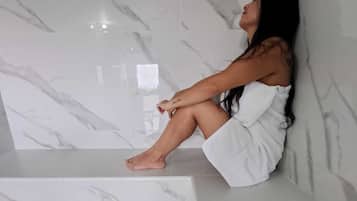 Features a large sink, sleek faucet, and marble-patterned walls.
