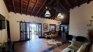 A spacious living area with a high wooden ceiling, tiled flooring, and a seating arrangement including a sofa and chairs. - Country House Hotel (Guatapé)