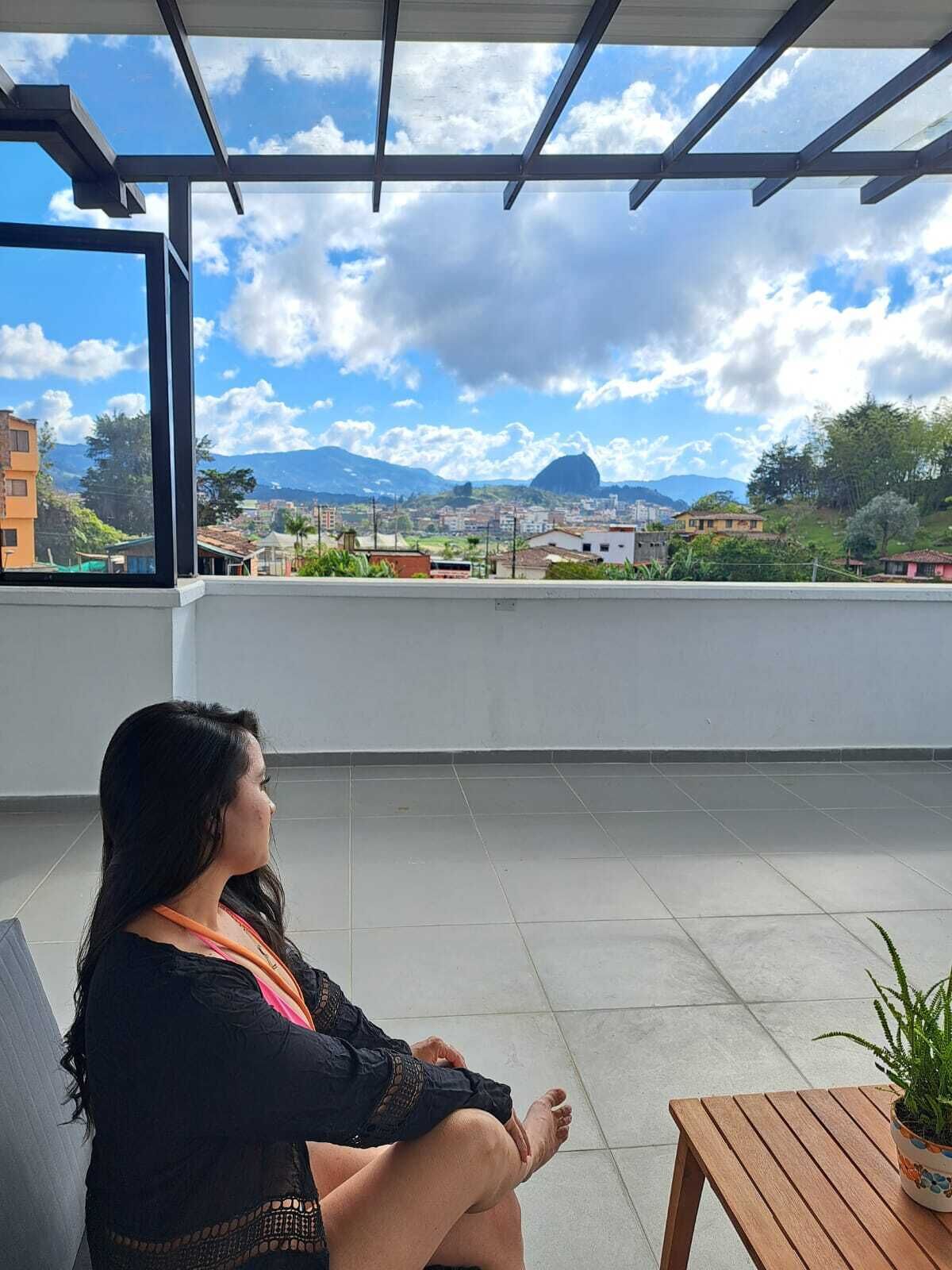 A person sitting on a balcony with a view of a cityscape and mountains.
