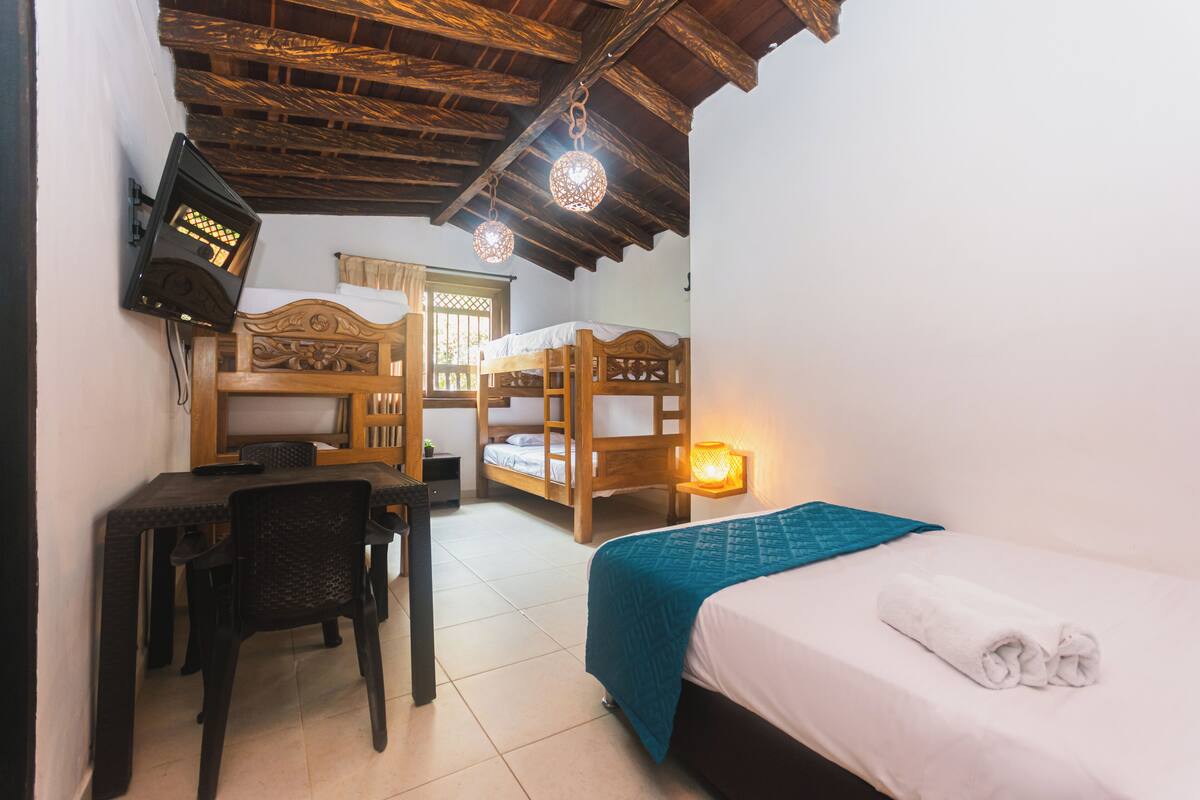 A room with a bed, a desk, and two bunk beds.