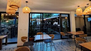 An indoor dining area with wicker chairs and tables, large windows, and hanging wicker lamps. - Country House Hotel (Guatapé)