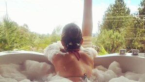 A person relaxing in a hot tub filled with bubbles, surrounded by greenery. - Country House Hotel (Guatapé)