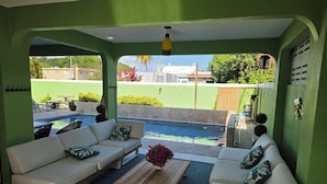 A room with a pool, green walls, white sofas, and a wooden coffee table. - Spacious 5-bedroom house in gated community, private pool and semi-private beach (Humacao)
