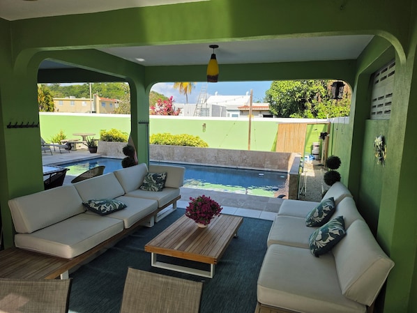 Une pièce avec une piscine, des murs verts, des canapés blancs et une table basse en bois.