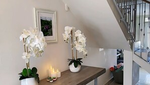 A modern living room with a wooden bench, white orchids, candles, and a framed picture on the wall. - Spacious 5-bedroom house in gated community, private pool and semi-private beach (Humacao)