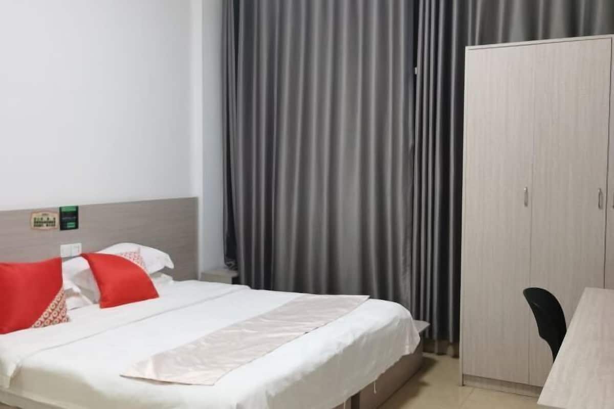 A hotel room with a bed, a wardrobe, and a desk.