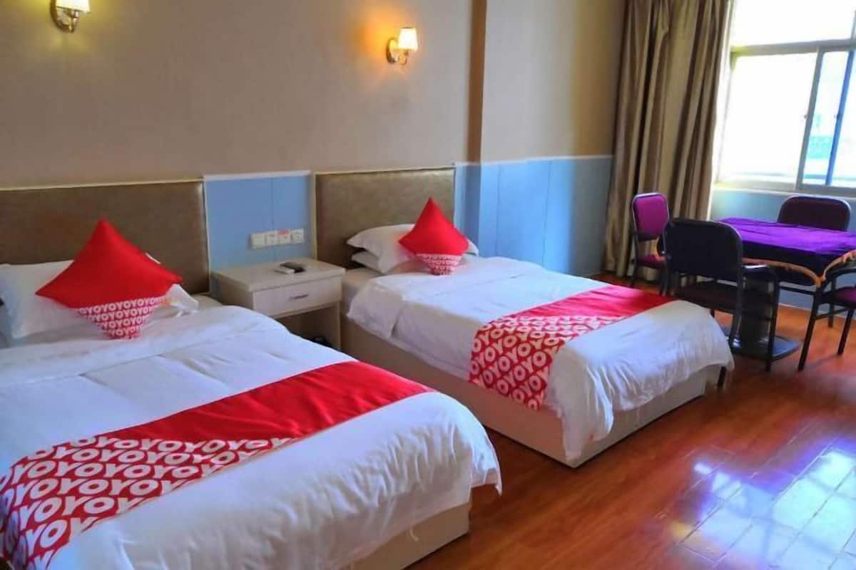 A hotel room with two beds, a desk, and a chair.