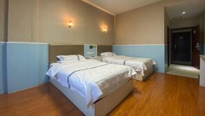 Habitación de hotel con dos camas, suelo de madera y lámparas fijadas a la pared.