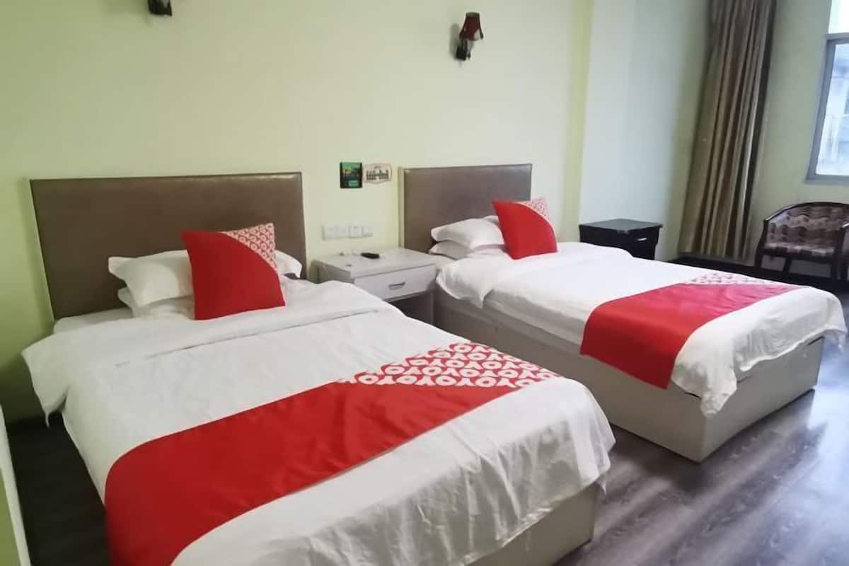 Two beds with red and white bedding, a nightstand, a small table, and a chair.