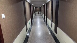 Un largo y estrecho pasillo con piso pulido y paredes oscuras, que conduce a una puerta al final.