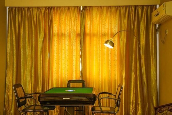 A room with a green pool table, two chairs, and a lamp.