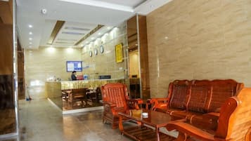 A hotel lobby with a reception desk, seating area, and a television screen.
