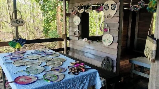 A rustic wooden structure with a table displaying various handcrafted items, including plates and jewelry. - Kajoro Sunset Lodge  (Vangunu Island)