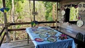 A covered outdoor area with a table displaying various plates and bowls, surrounded by wooden railings and a forest backdrop. - Kajoro Sunset Lodge  (Vangunu Island)