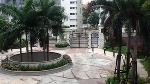 A courtyard with palm trees, a circular garden, and a gated entrance. - Palm Tree Genlex Condo (Pasay)