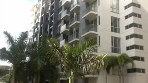 A multi-story residential building with balconies, surrounded by palm trees. - Palm Tree Genlex Condo (Pasay)