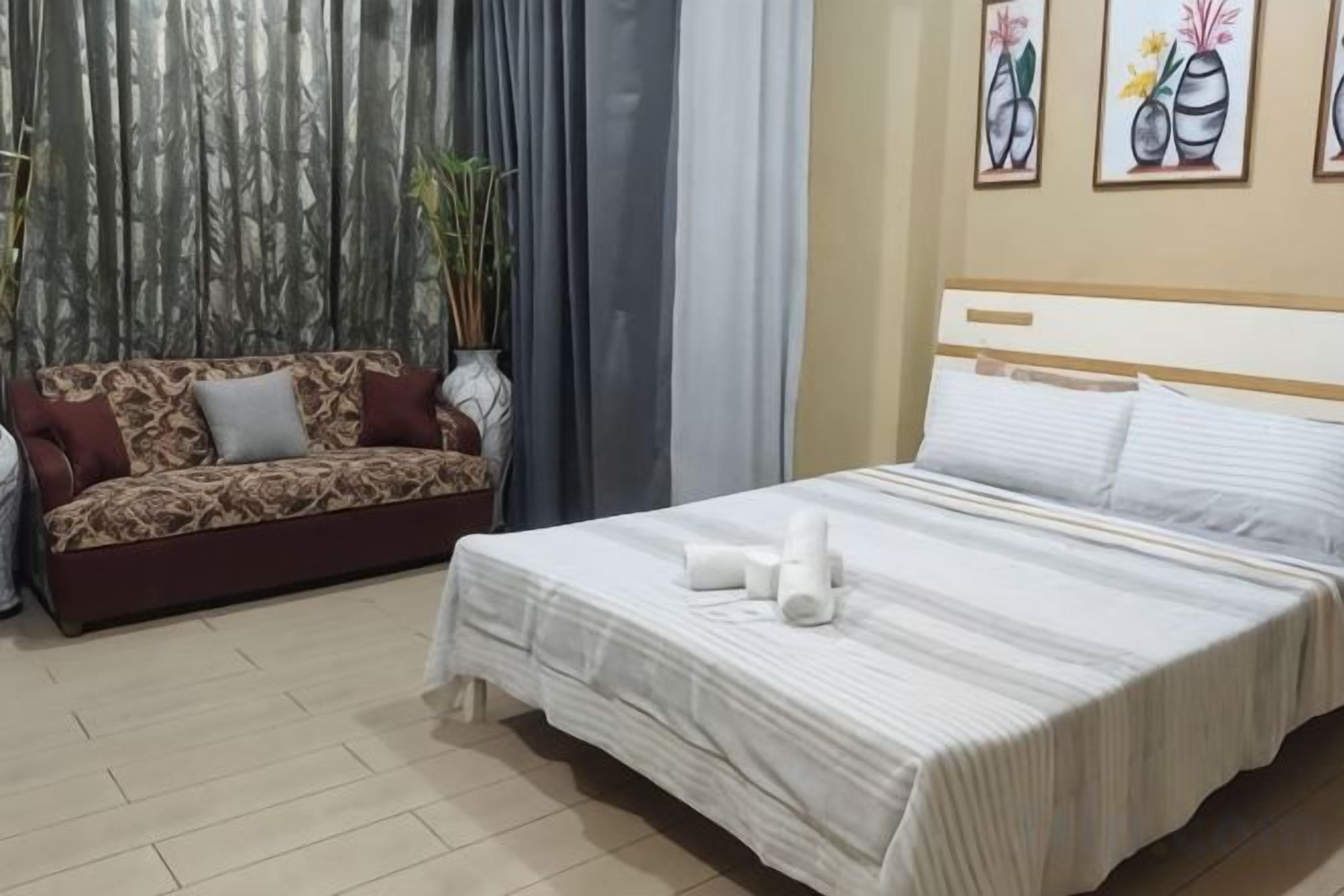 A hotel room with a bed, a sofa, and curtains.