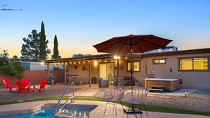 A backyard with a swimming pool, red chairs, a hot tub, and a covered patio area with string lights. - Mountain views! Big private yard with pool - heat optional with fee & spa! (Tucson)