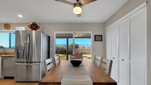 A modern kitchen with a stainless steel refrigerator, a dining table with chairs, and a view of the outdoors through glass doors. - Mountain views! Big private yard with pool - heat optional with fee & spa! (Tucson)