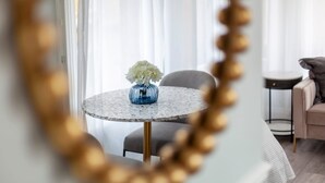Et moderne værelse med et rundt marmorbord, en blå vase med hvide blomster, en grå sofa og et lille rundt bord med sort fod.