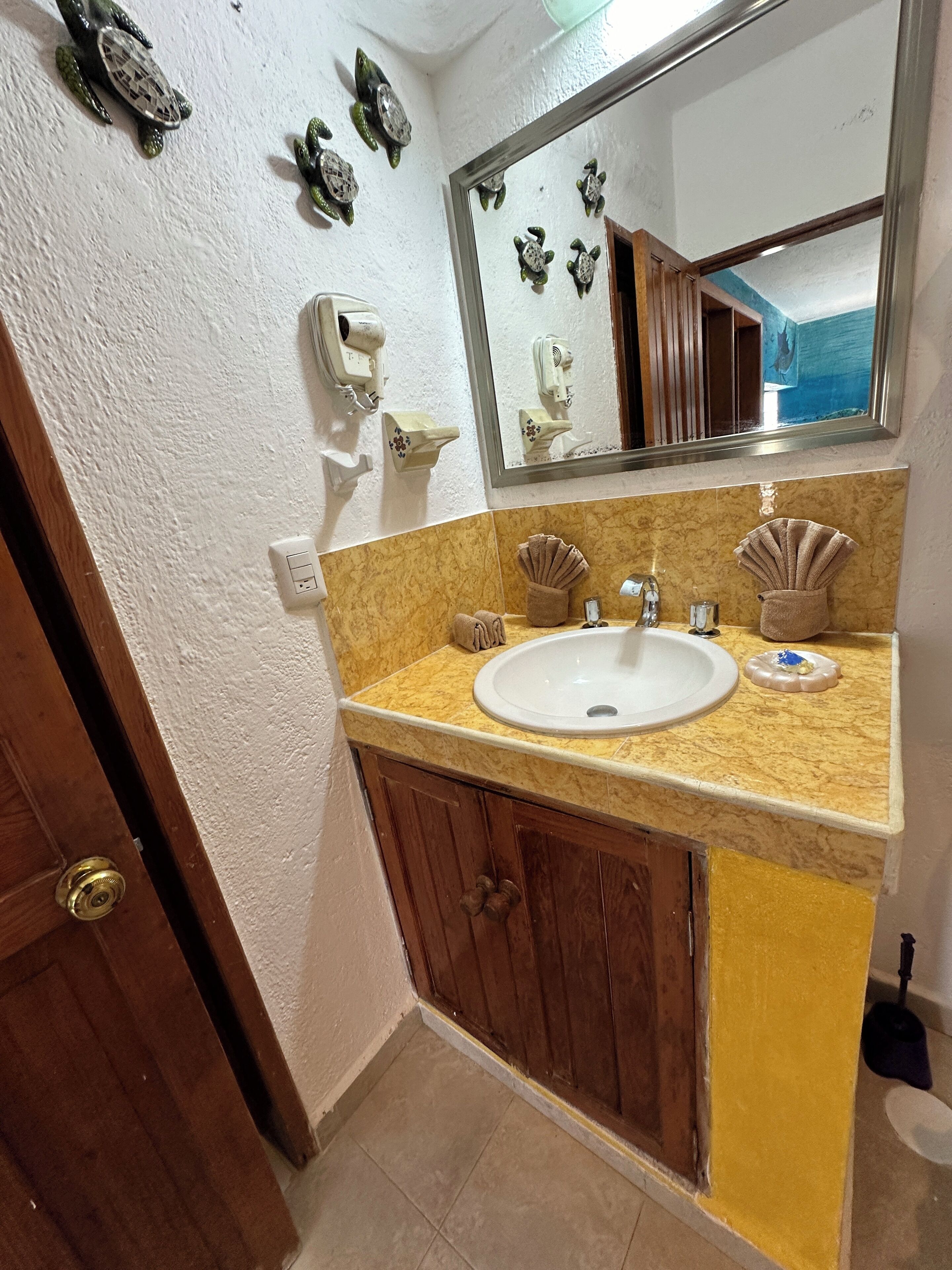 A bathroom with a sink, vanity, and decorative shells. There is a mirror above the sink and a towel rack.