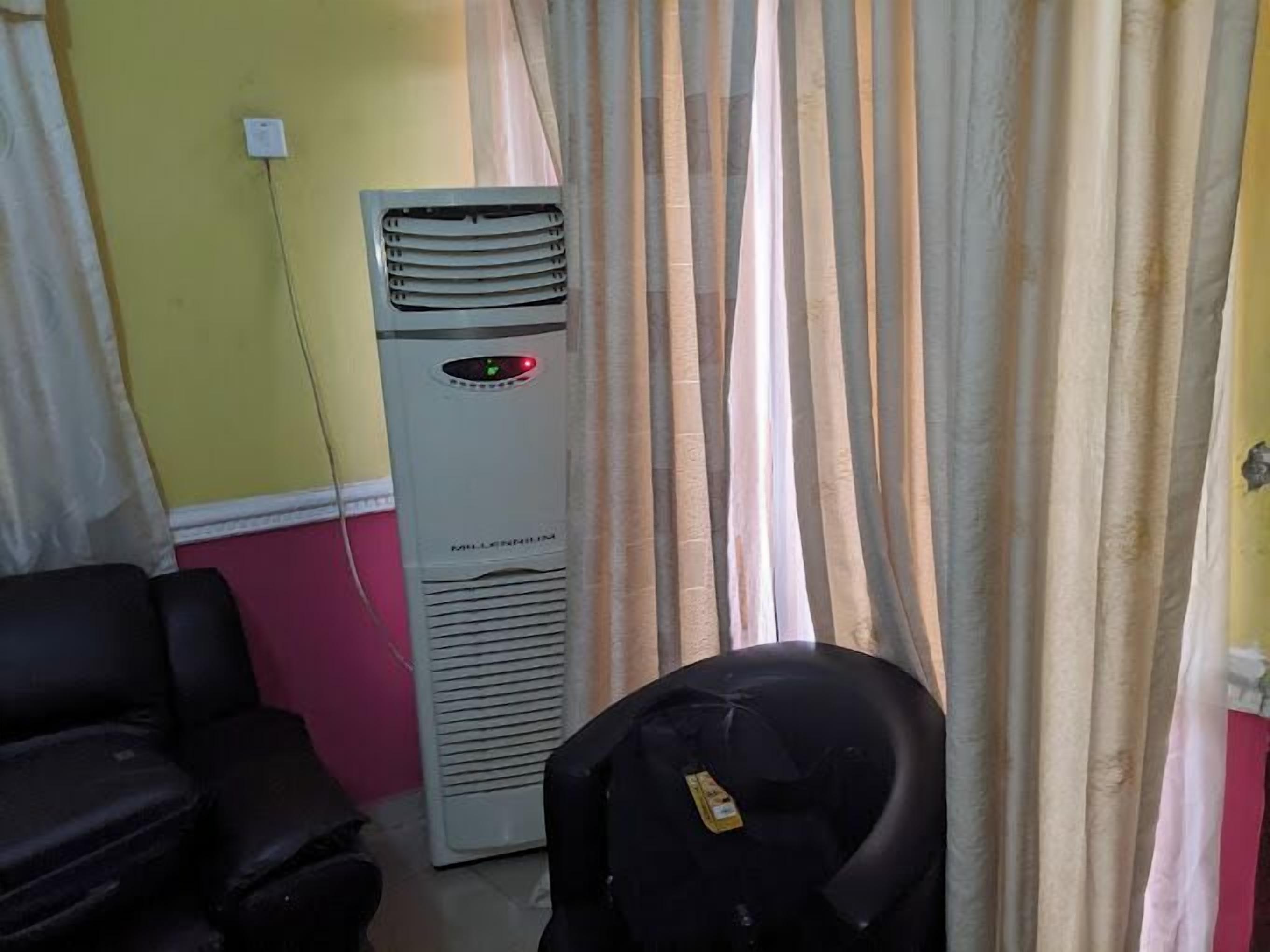 Una habitación con un aire acondicionado grande, una silla de oficina negra y una pared roja.