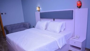 Un dormitorio con una cama grande, una mesita de noche, una lámpara y un aplique de pared.