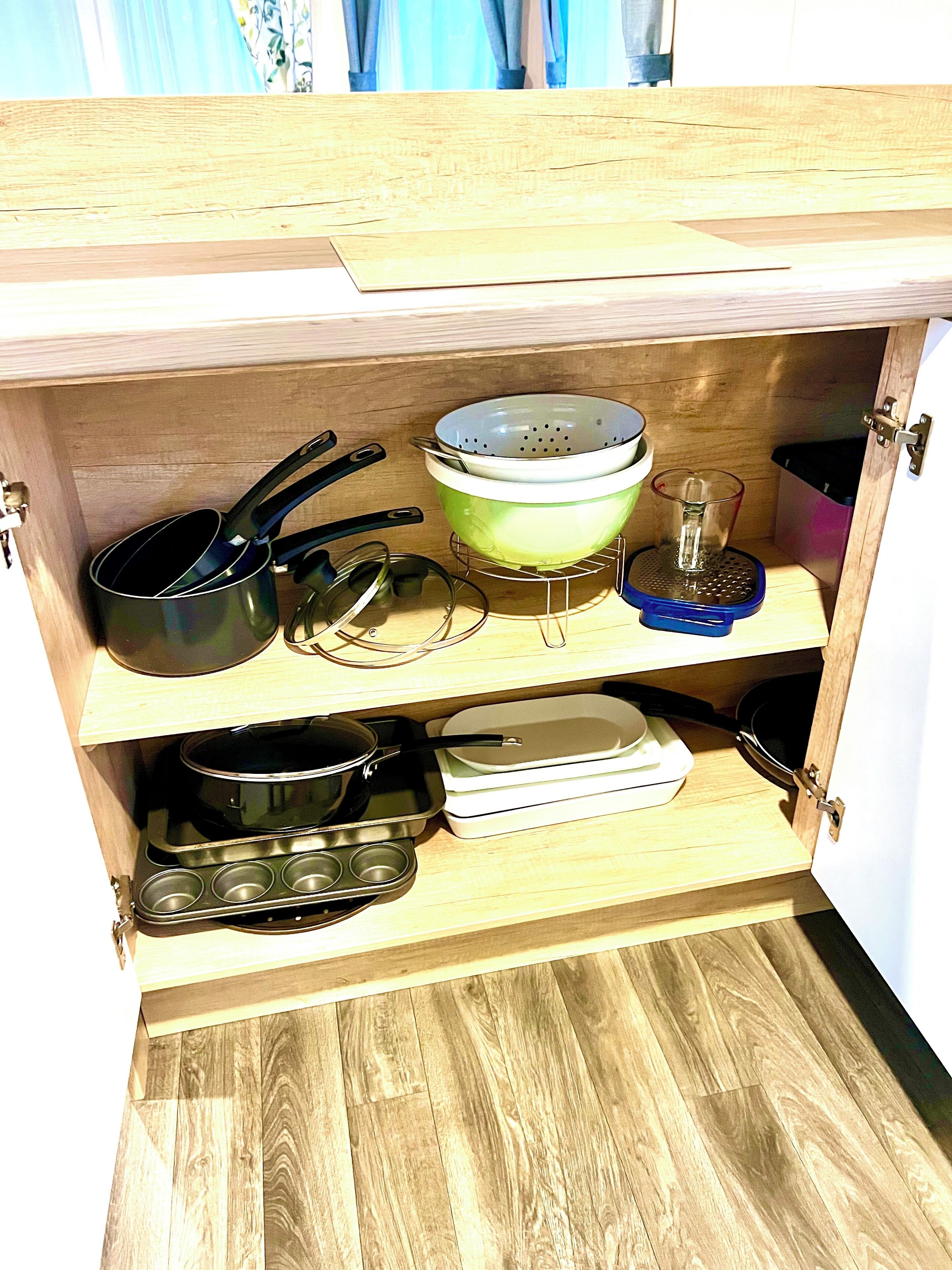 A wooden kitchen cabinet with various cookware and dishes.