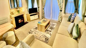 Een moderne woonkamer met een zithoek, een televisie, een open haard en een eethoek.