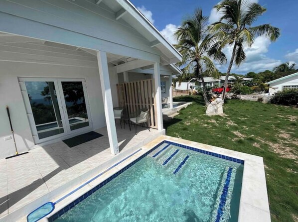A modern house with a swimming pool, covered patio, and palm trees.