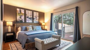 A bedroom with a bed, bedside lamps, a bench, a rug, and a view of the outdoors. - Desert Skies - Beautiful private Tucson home with great mountain views &  pool (Tucson)