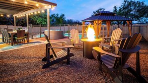 An outdoor patio area with Adirondack chairs, a fire pit, and a covered seating area. - Desert Skies - Beautiful private Tucson home with great mountain views &  pool (Tucson)