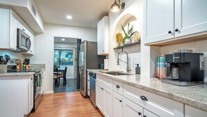 A modern kitchen with white cabinets, a microwave, a coffee maker, and a dishwasher. - Desert Skies - Beautiful private Tucson home with great mountain views &  pool (Tucson)