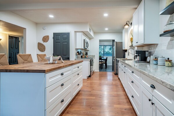 Une cuisine moderne avec des meubles blancs, des plans de travail en bois et un îlot central.