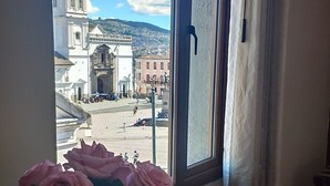 A window with a view of a historic building and a vase of pink roses on a glass table. - Real Audiencia Hotel  (Quito)