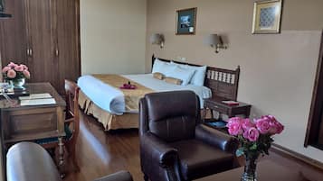 Una habitación de hotel con cama, escritorio, silla y mesita de noche.