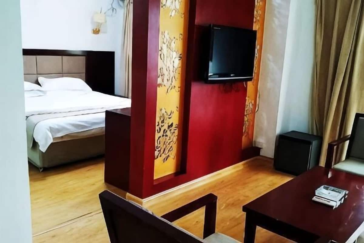 A hotel room with a bed, a TV, a table, and a chair.