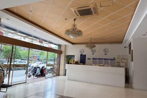 A hotel lobby with a reception desk, glass doors leading outside, and a ceiling with recessed lighting. - Pingnan Xiangyue Hotel (Pingnan)