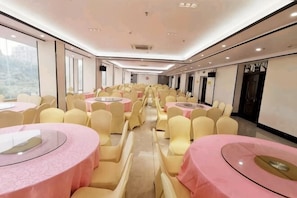 A banquet hall with round tables, yellow chairs, and pink tablecloths. - Pingnan Xiangyue Hotel (Pingnan)