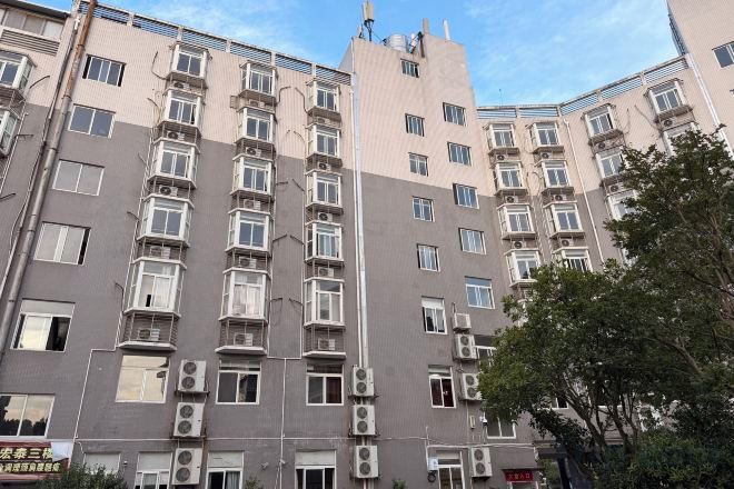 Un edificio de varios pisos con fachada simétrica, múltiples ventanas y unidades de aire acondicionado.
