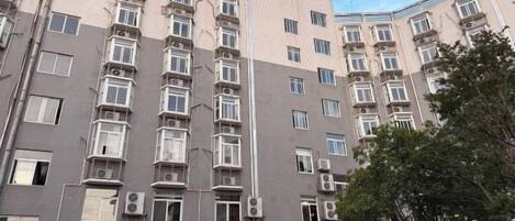 Un edificio de varios pisos con fachada simétrica, múltiples ventanas y unidades de aire acondicionado.