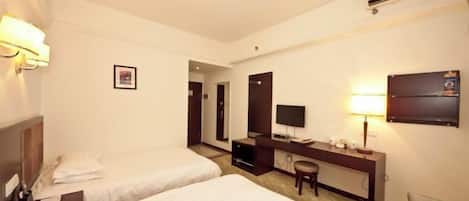 Habitación de hotel con dos camas, un escritorio con una silla, un televisor y un aire acondicionado.