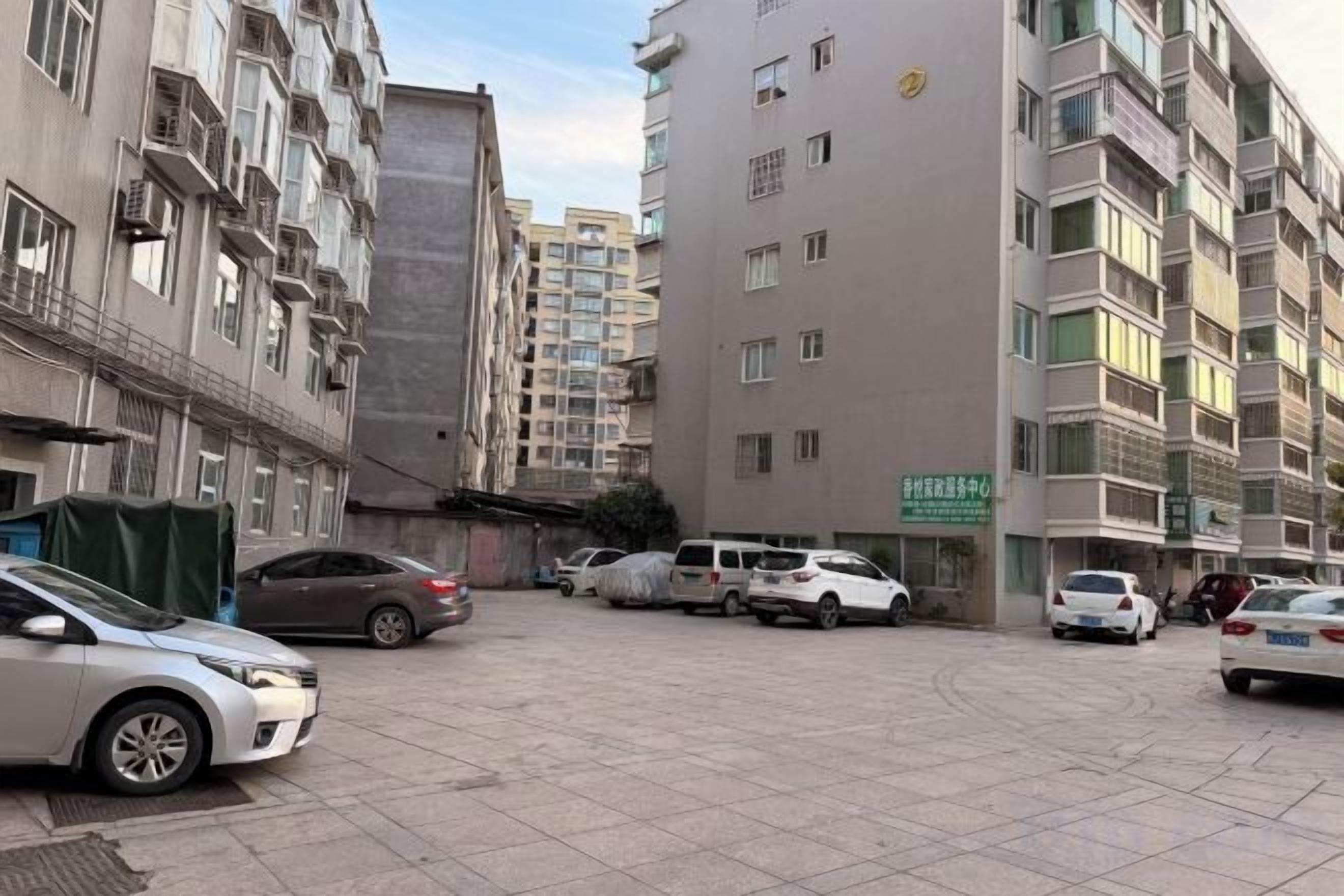 A multi-story residential building with a parking area in front.