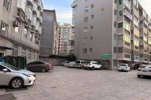A multi-story residential building with a parking area in front.